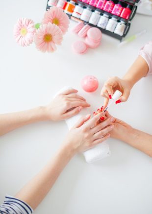 Woman in salon receiving manicure by nail beautician