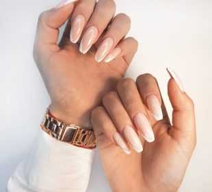 Gentle camouflage gel polish on long square nails with a French design. Hands with a professional manicure in a shirt. Trendy nail extension with French design.
